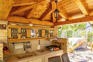 A wooden interior with a kitchen area, including cabinets, a sink, and a grill. - Pool and Garden Apartment Hortenzija (Kostrena)