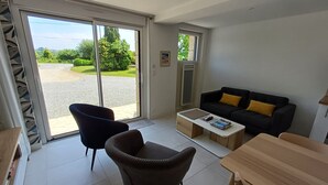 En moderne stue med sofa, lænestol, sofabord og en skydedør, der fører til en indkørsel.