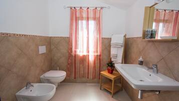 Une salle de bain équipée d’un bidet, de toilettes, d’un lavabo et d’un rideau de douche.
