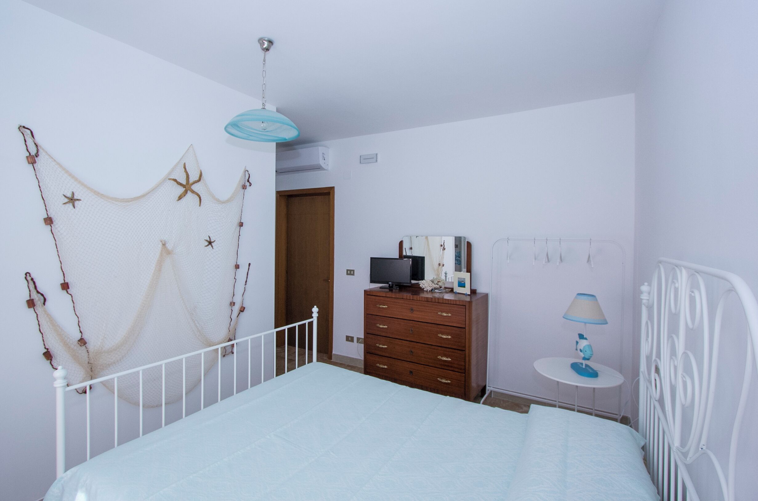 Un dormitorio con cama, cómoda, televisor y un adorno en la pared.