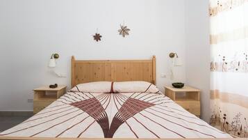 Een bed met een beddengoed met een geometrisch patroon, een houten hoofdbord, twee nachtkastjes met lampen en wanddecoraties.