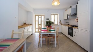 A modern kitchen with white cabinets, a wooden dining table, and a hanging light fixture. - LA PERLA D'ABRUZZO (Cugnoli)
