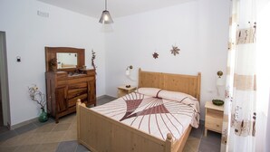 A bedroom with a wooden bed, a dresser, a nightstand, a mirror, and a hanging light fixture. - LA PERLA D'ABRUZZO (Cugnoli)