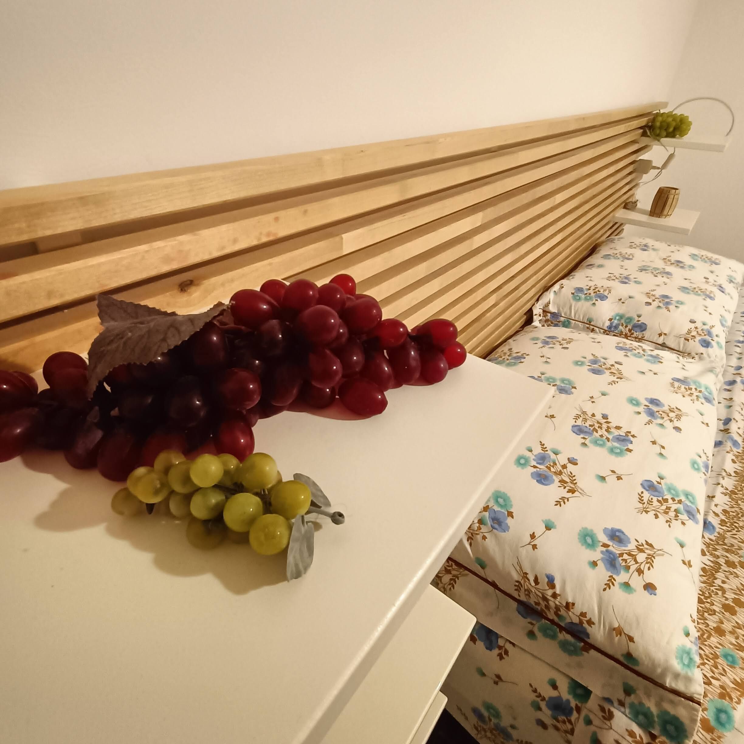 A bed with a floral-patterned pillow and a wooden headboard.