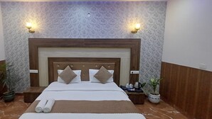 A hotel room with a wooden headboard, two wall-mounted lights, a bed with white linens, and two potted plants. - Hotel Amour Chandigarh Zirakpur (Zirakpur)