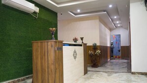 A reception desk with a wooden finish, a green wall, and a marble floor. - Hotel Amour Chandigarh Zirakpur (Zirakpur)