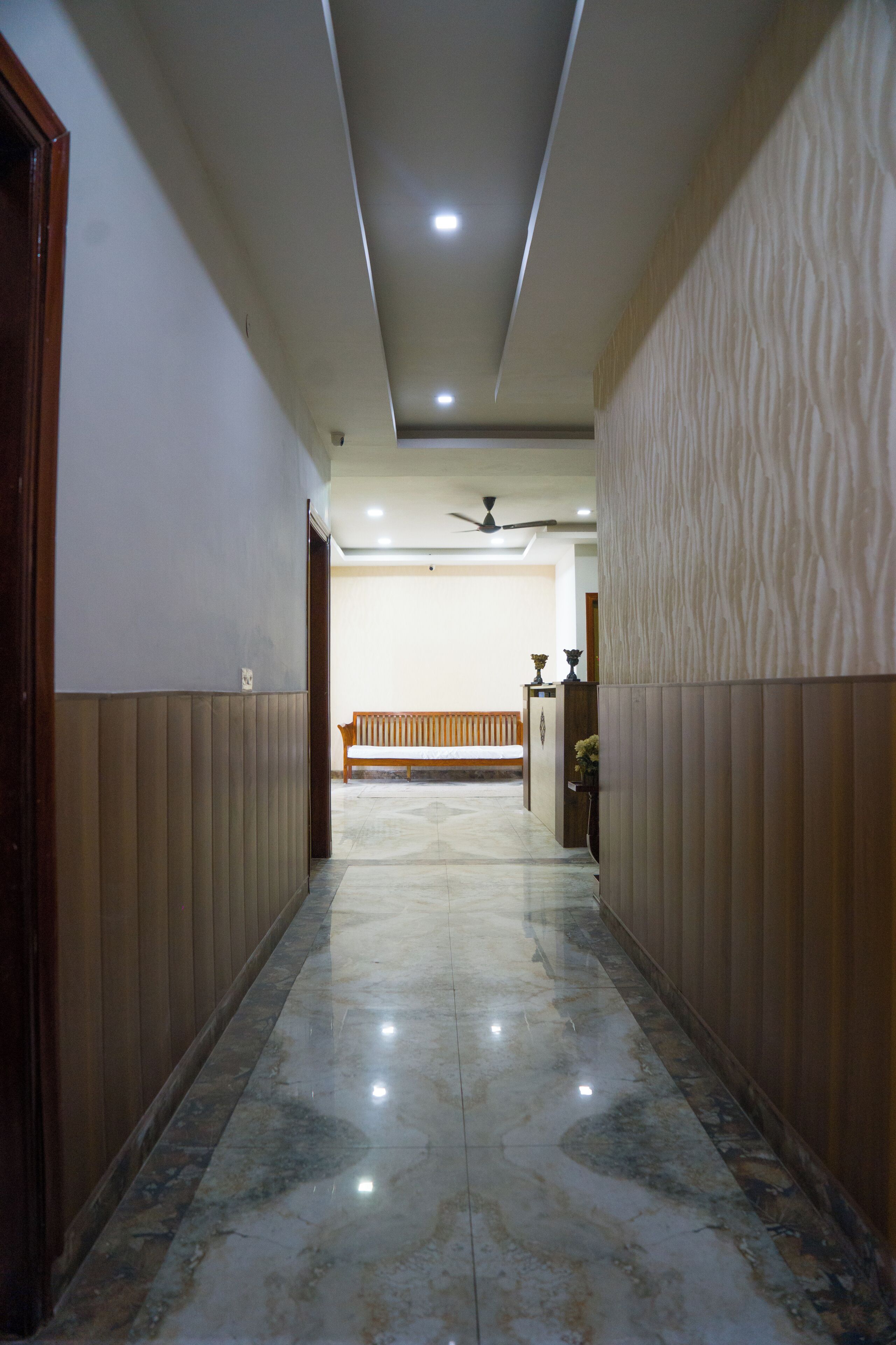 A hallway with a wooden bench, a ceiling fan, and a tiled floor.