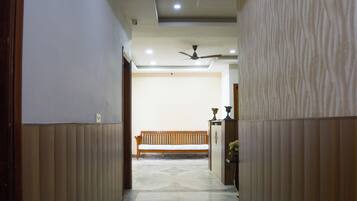 A hallway with a wooden bench, a ceiling fan, and a tiled floor.