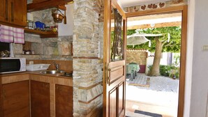 A kitchen with stone walls, wooden cabinets, a sink, and a microwave. - Stone House Only 150m From the sea (Umag)