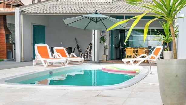 Ein Swimmingpool mit Liegestühlen, einem Tisch und einem großen Sonnenschirm.
