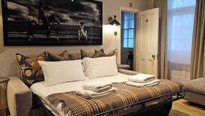 A hotel room with a bed, a painting, a lamp, a door, and a window. - Luxury Central London Apartment  Craven Street (London)