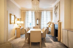 A dining room with a long table, chairs, a chandelier, and a fireplace. - Luxury Central London Apartment  Craven Street (London)