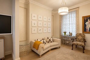 A living room with a sofa, armchair, artwork on the wall, and a television. - Luxury Central London Apartment  Craven Street (London)