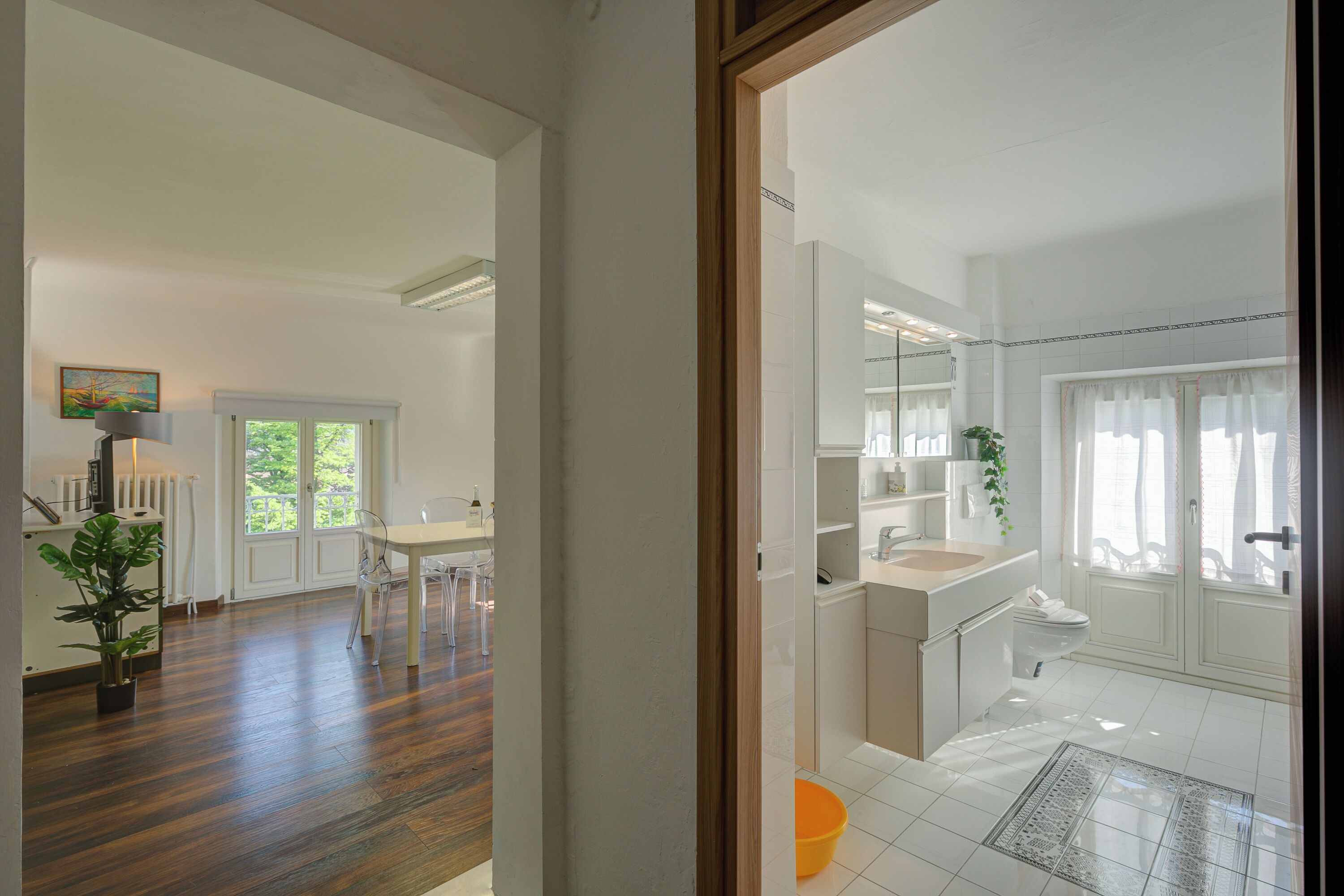 Une cuisine moderne avec des meubles blancs, un coin repas doté d’une table et de chaises blanches, et une salle de bain avec un lavabo et des toilettes blancs.
