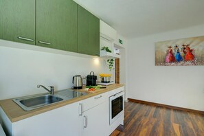 A modern kitchen with a sink, stove, and green cabinets.