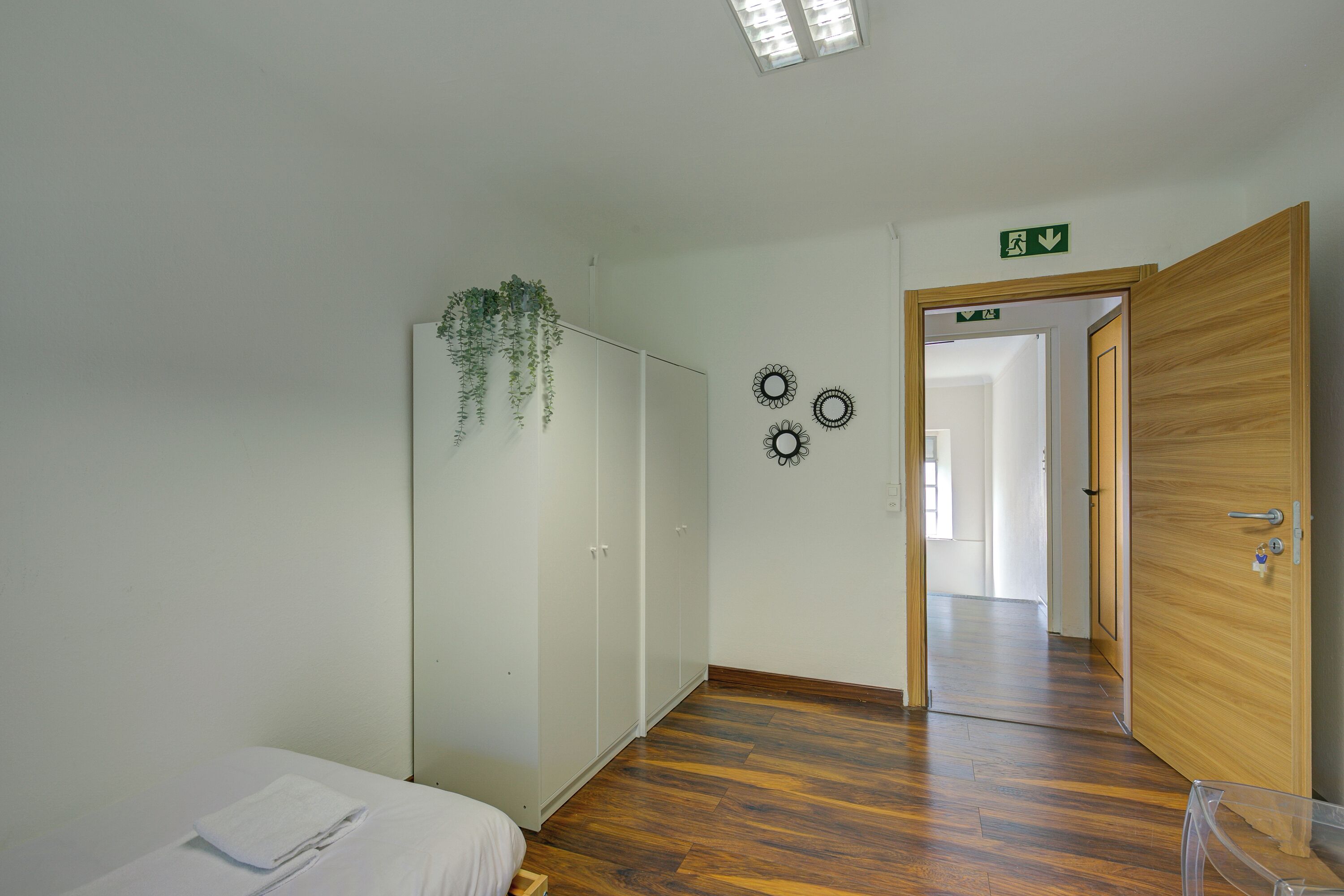 Una habitación con cama, armario, espejo y una puerta que da a otra estancia.