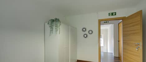 Una habitación con cama, armario, espejo y una puerta que da a otra estancia.