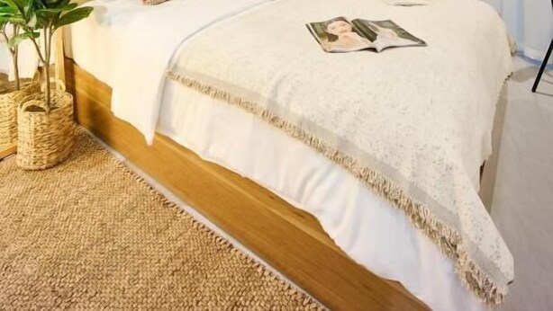Une chambre à coucher bien rangée, avec un lit, des tables de chevet, un miroir et des œuvres d’art accrochées au mur.