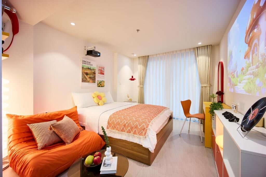 A hotel room with a bed, a sofa, a desk, and a TV screen.