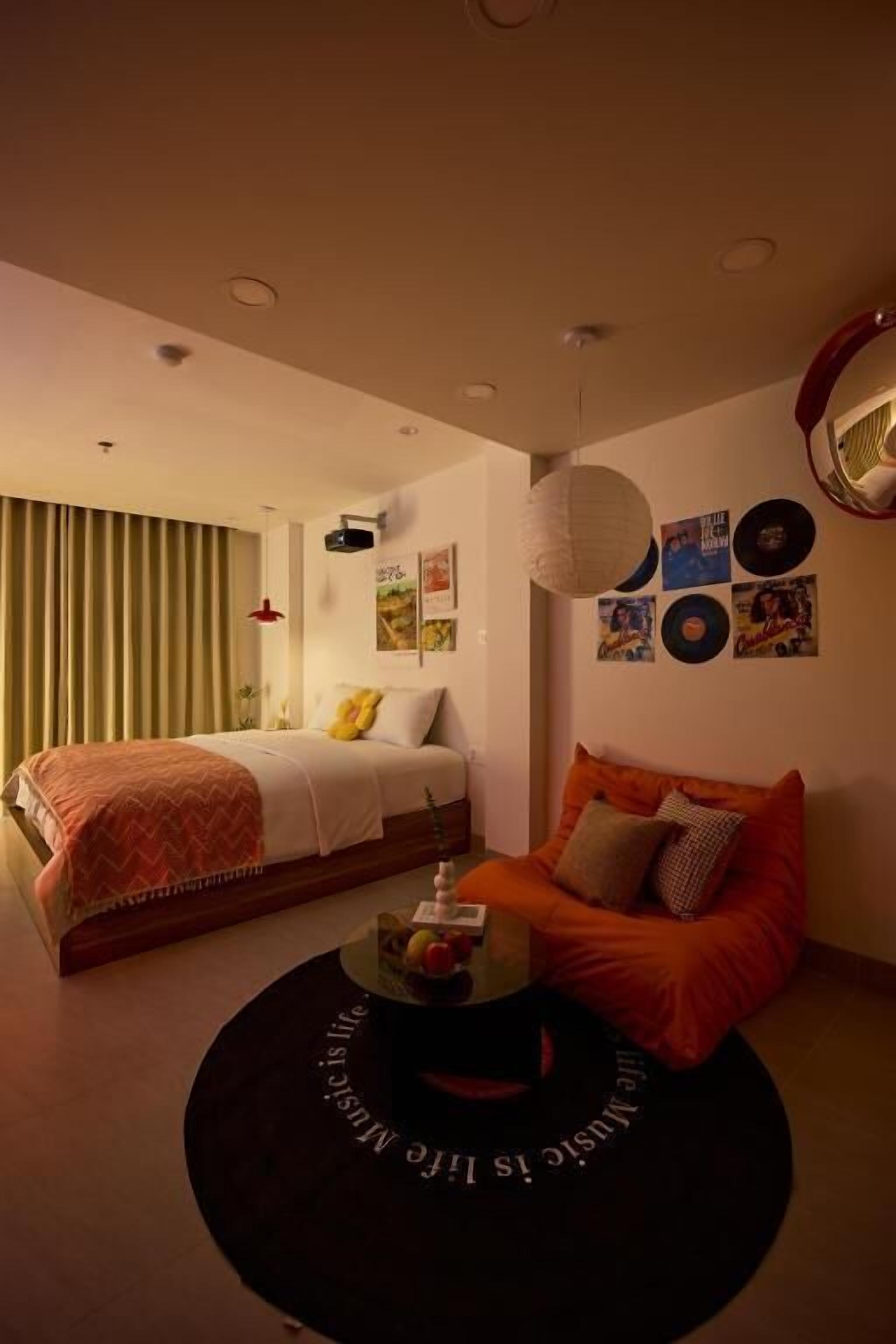 A bedroom with a bed, a sofa, a coffee table, and wall decorations including vinyl records.