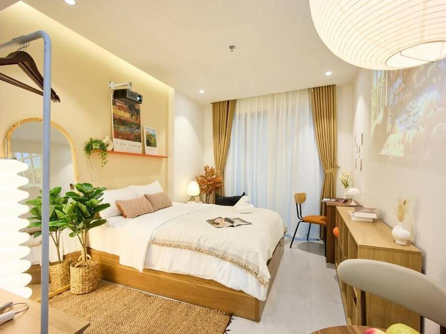 A bedroom with a bed, bedside table, lamp, and a large mirror.