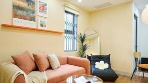 Un salon avec un canapé, une table basse, un miroir et une fenêtre avec des barreaux.
