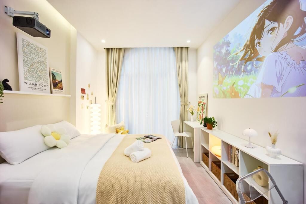 A hotel room with a bed, a desk, a bookshelf, and a large window with curtains.
