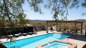 Una piscina con hidromasaje, sillas de descanso y vistas al paisaje desértico.