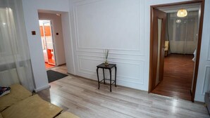 A room with a wooden floor, white walls, a small table with a vase, and a door leading to another room. - Barrique Eminescu 14 (Brașov)