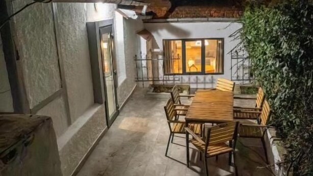 An outdoor patio with a wooden table and chairs, a door, and a window with lights on. - Barrique Eminescu 14 (Brașov)