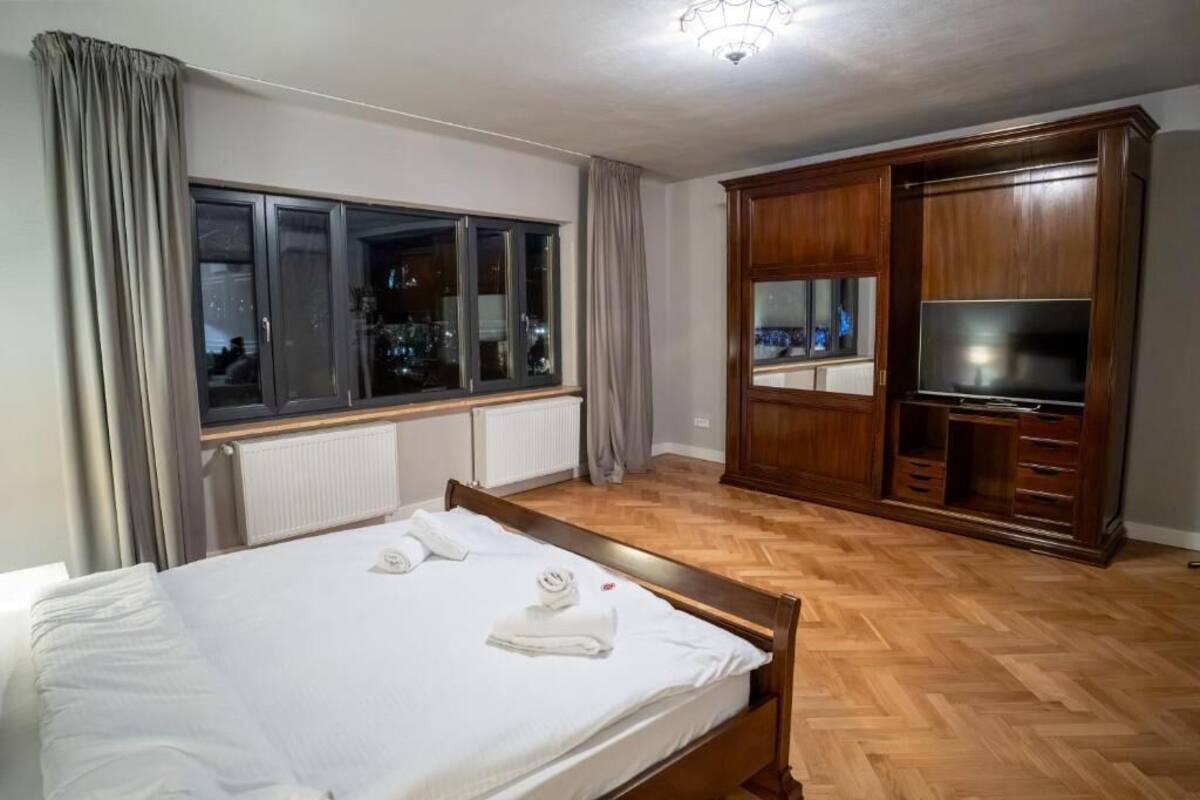 Una habitación de hotel con cama, televisor, armario y ventana con cortinas.