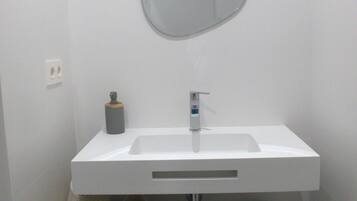 A bathroom with a white sink, a mirror, a towel, and a trash can.