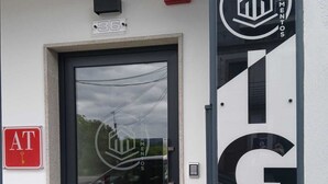 En byggnadsentré med en glasdörr, en brandlarm och en skylt med en logotyp och ett telefonnummer.
