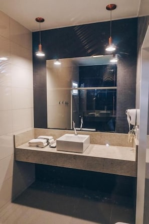 Un baño moderno con un espejo grande, dos lavamanos e iluminación colgante.