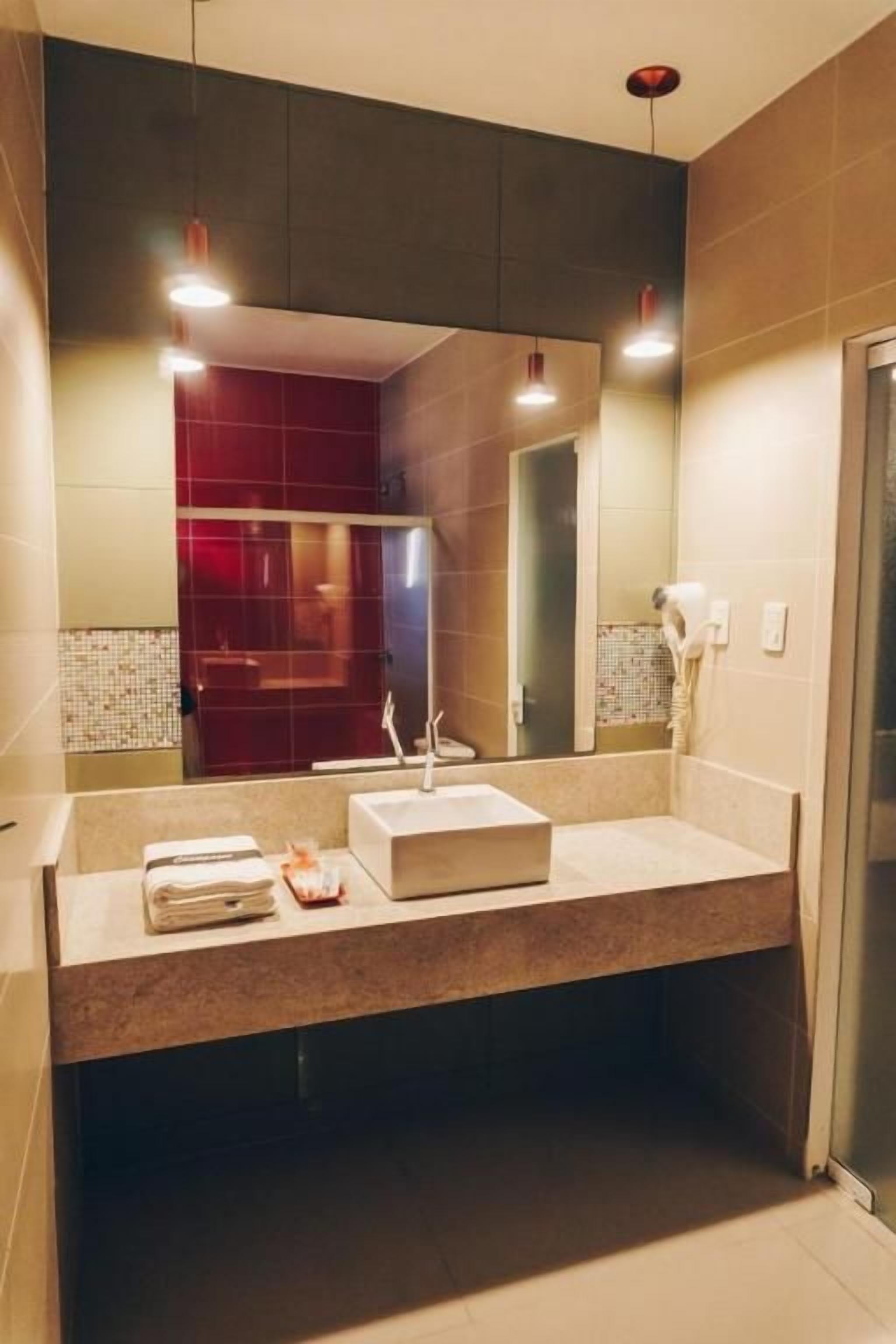A modern bathroom with a large mirror, two sinks, and a towel rack.