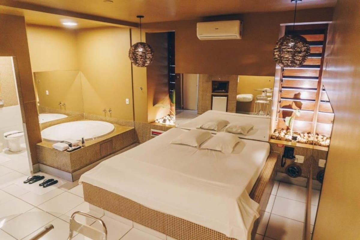 Habitació d'hotel amb un llit gran, una banyera, un mirall i una cuineta.