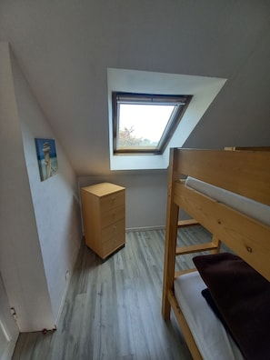 A small room with a sloped ceiling, a skylight, a wooden bunk bed, a small wooden dresser, and a painting on the wall. - Seaside fisherman's house Paimpol (paimpol)