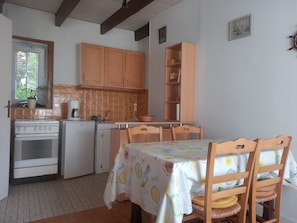 Une cuisine avec des meubles de rangement en bois, une table à manger avec des chaises, une cuisinière et un réfrigérateur.