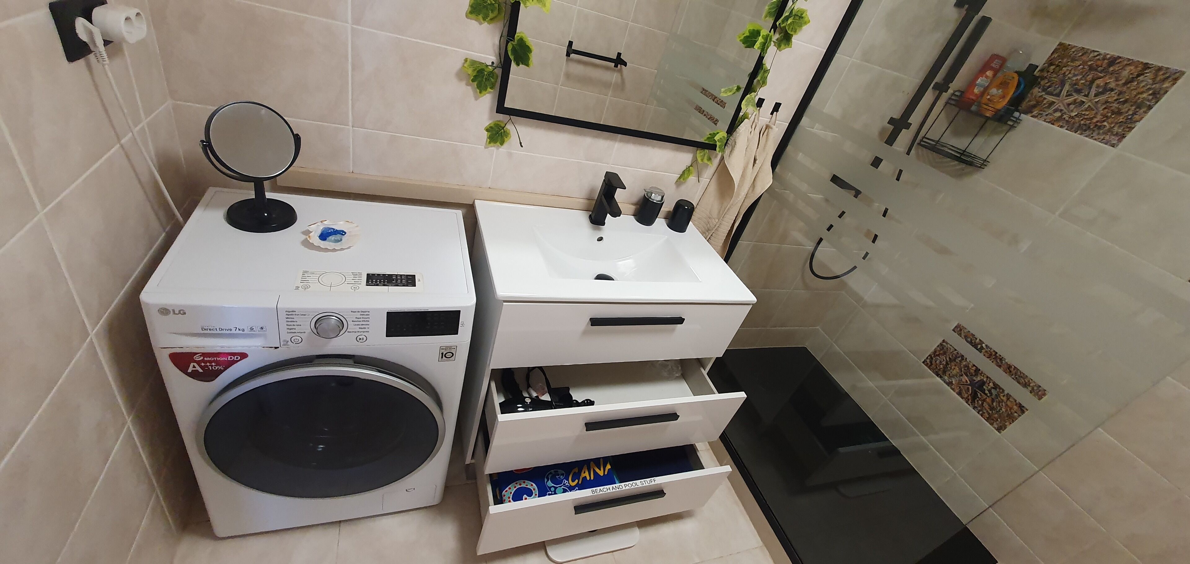Ein kleines Badezimmer mit Waschmaschine, Waschbecken und Spiegel.