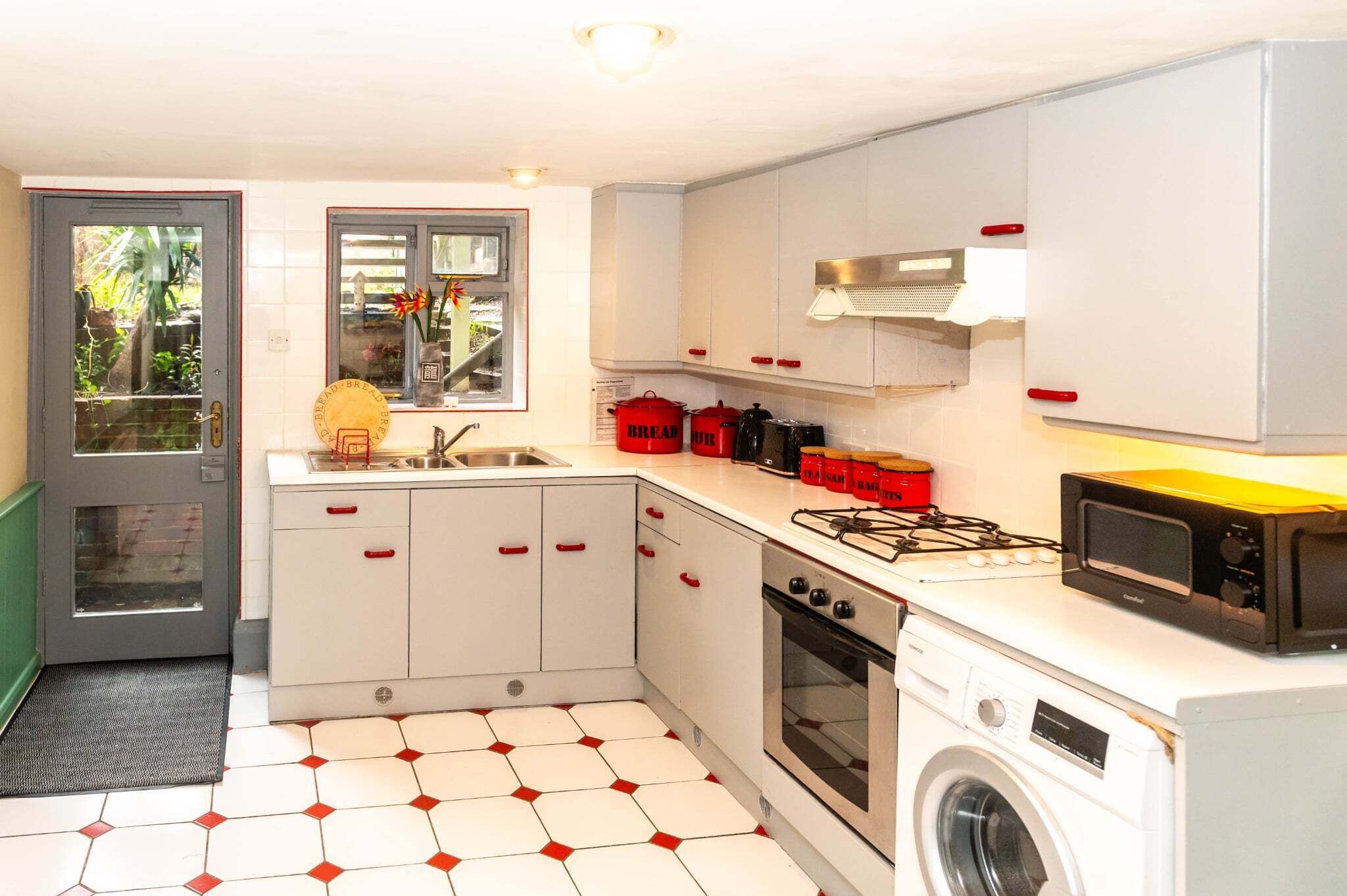 A compact kitchen with a washing machine, a microwave, and a gas stove.