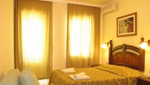 Ein Hotelzimmer mit Bett, einer Couch, Vorhängen, einem Gemälde und einem Nachttisch.
