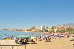 A beach with people, umbrellas, and buildings in the background. - Amazing Villa with outstanding Sea views. Near from all amenities (Benalmadena)