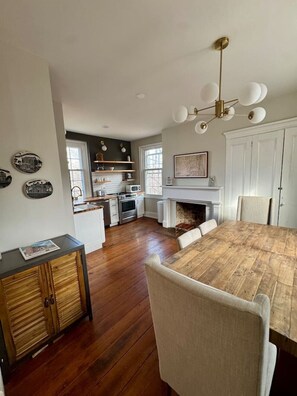 A spacious kitchen with a dining area, wooden flooring, and a fireplace. - Historic DT Lynchburg Apt, Walk To Shops & Dining (Lynchburg)