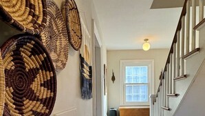A wooden staircase with white railings leading to a room with a window. - Historic DT Lynchburg Apt, Walk To Shops & Dining (Lynchburg)