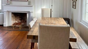 A dining area with a wooden table, chairs, a fireplace, and a chandelier. - Historic DT Lynchburg Apt, Walk To Shops & Dining (Lynchburg)
