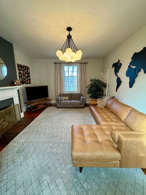Ein Wohnzimmer mit einer Couch, einem Fernseher, einem Kamin und einer Weltkarte an der Wand.