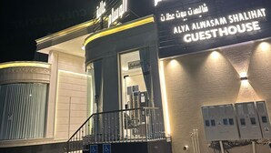 Entrada de un hotel con un letrero que dice 'Alya Alwasam Shalihat Guesthouse' y una rampa accesible para sillas de ruedas.