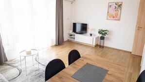 A modern living room with a TV, dining table, chairs, a small plant, and a painting on the wall. - Apartments Amare / Apartment 3 with Sea view (Neum)