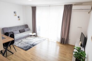 A modern living room with a grey sofa, a small round table, and a TV.