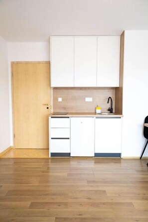 A kitchen with white cabinets, a wooden countertop, and a black faucet.